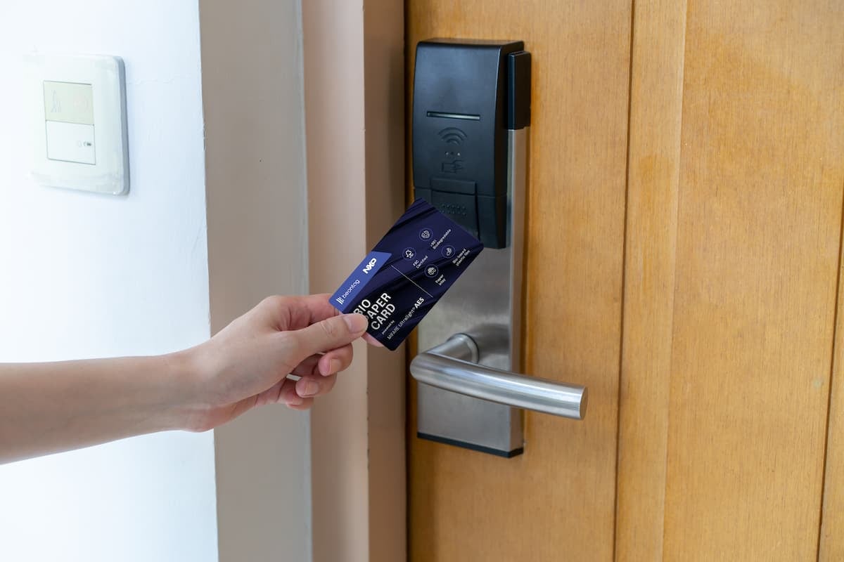 Person using an RFID key card to unlock a hotel room door with a contactless reader.