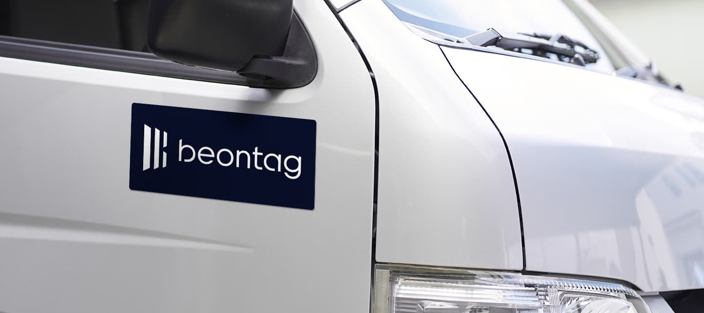 Beontag logo sticker on a white vehicle door, illustrating pressure-sensitive-adhesive labeling.