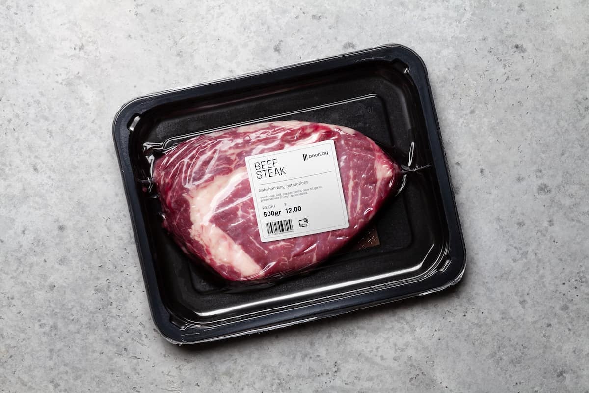 Vacuum-sealed beef steak in a black plastic tray with a Beontag security and product label on top, including weight, price, and handling instructions.