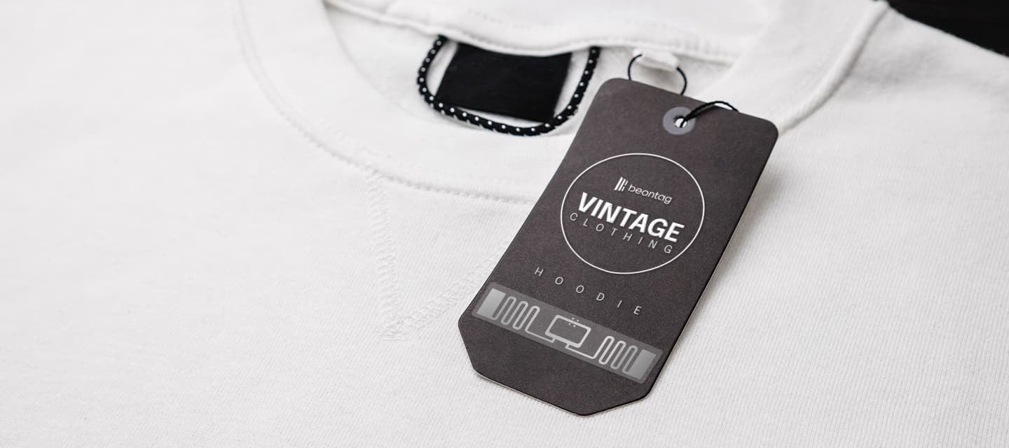 Close-up of a white hoodie with a Beontag vintage clothing RFID tag attached, showing smart labeling for fashion and retail traceability.