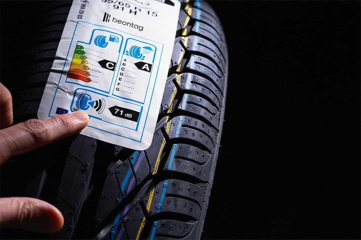 Pressure sensitive adhesive how to choose: close-up of a hand applying an EU tire label sticker onto a new car tire tread.